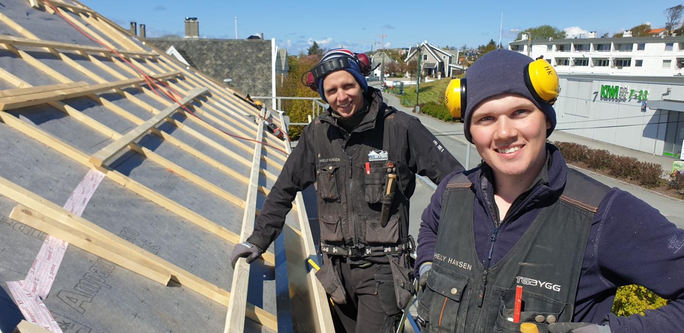 To blide arbeidere fra Nordbohus TG Bygg som monterer tak og smiler til kamera.