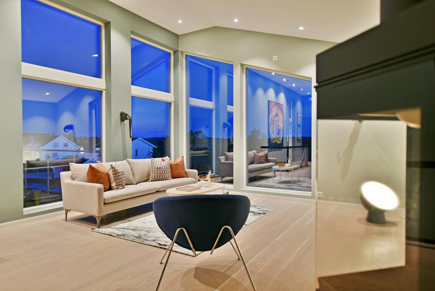 Stue med skrå vinduer i takhøyde i arkitekttegnet enebolig