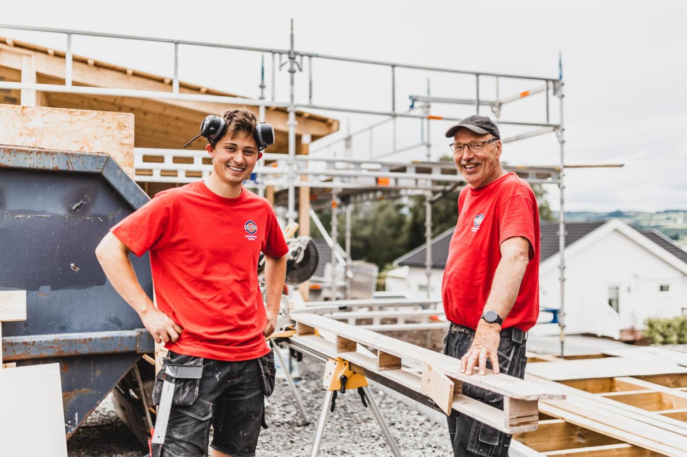 Ung og eldre mann bygger hus på byggeplass