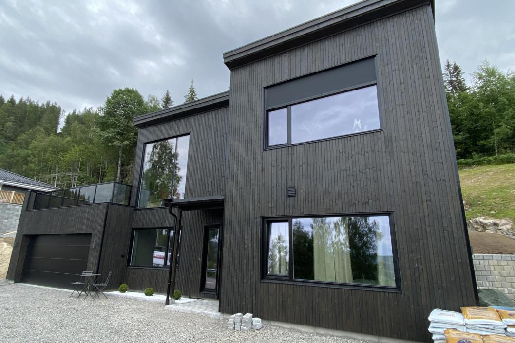 Moderne sort hus med flatt tak og sorte vinduskarmer