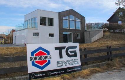 Bilde av hus etter rehabiliteringsjobb av Nordbohus TG Bygg. Stort skilt på gjerdet fremfor boligen som promoterer Nordbohus TG Bygg.