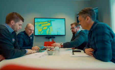 Fire personer rundt et møtebord med et kart over et boligområde på skjermen i bakgrunnen