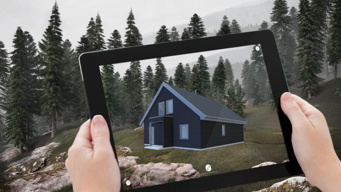 To hender holder et nettbrett og plasserer et hus på en tomt med AR-app