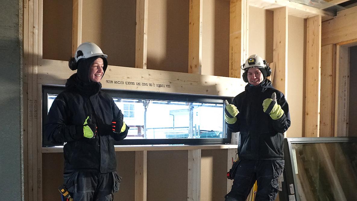 Tømrerlærling Erlend Åsen og hans kollega Kim André foran et vindu de nettopp har montert