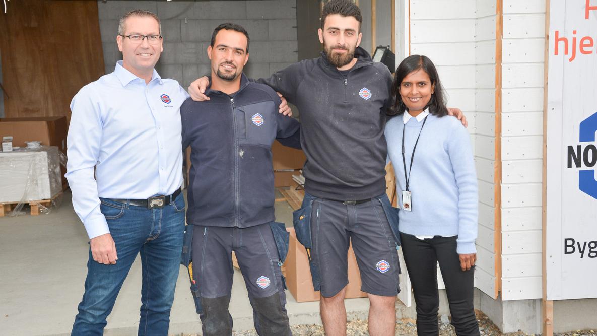 Bildet viser tre smilende Nordbohus-ansatte og en smilende fra Flyktningetjenesten på en byggeplass