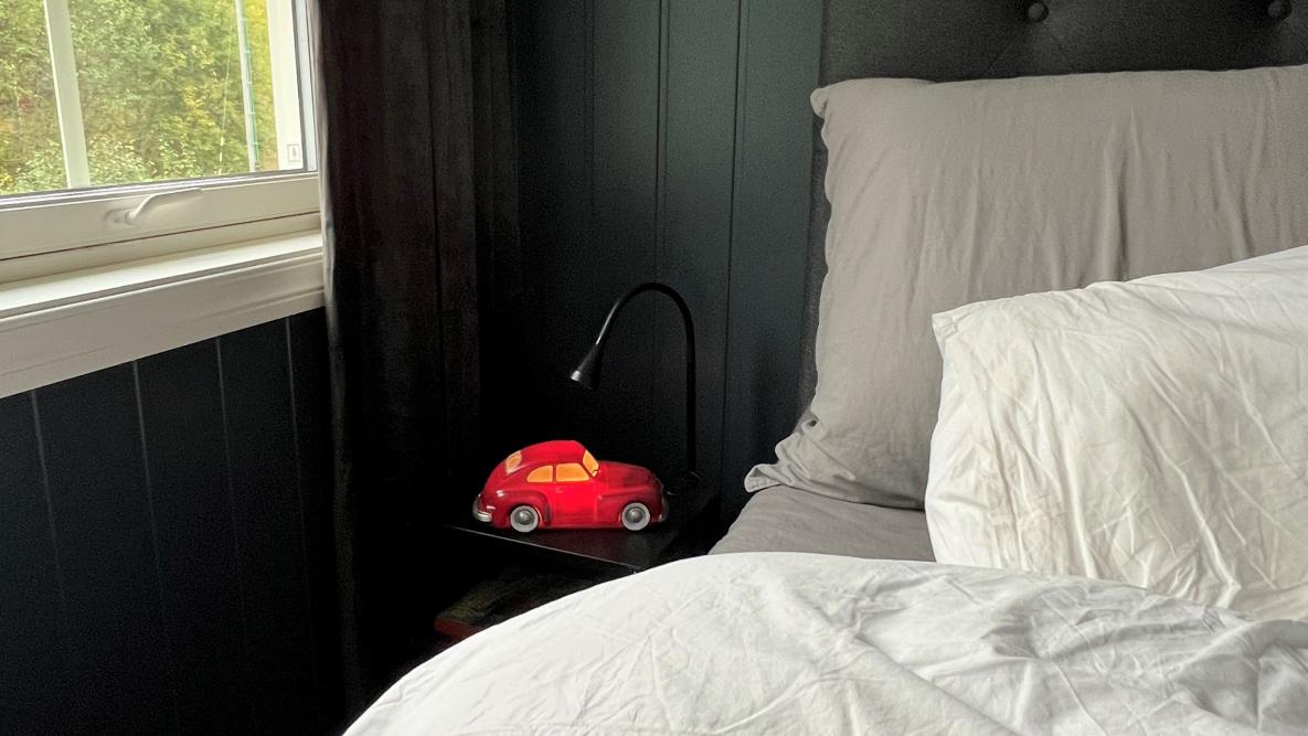 Bilde av seng ved et vindu og en billampe på et nattbord