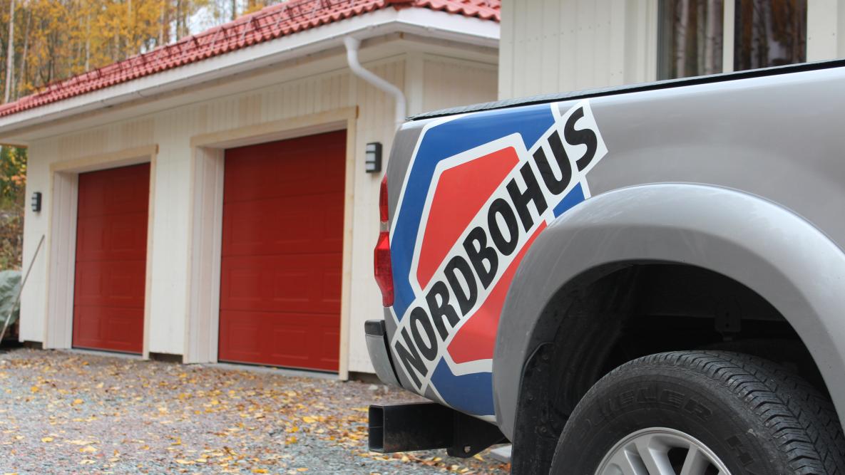 Bilde av bil med Nordbohus logo og garasje i bakgrunnen