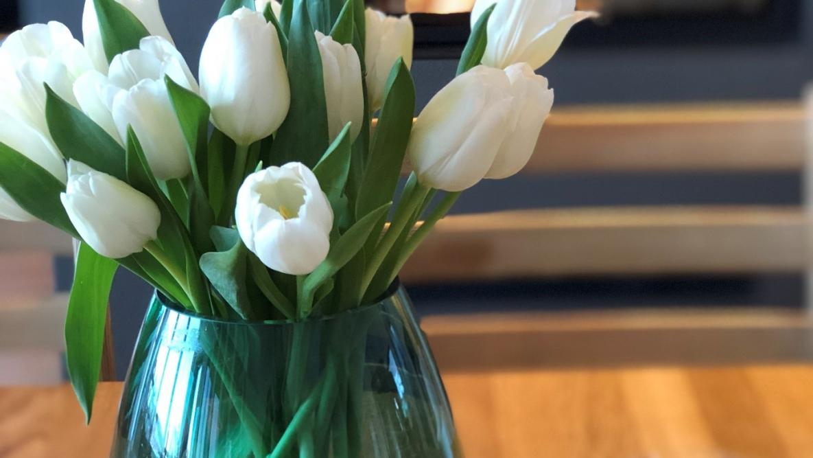 Bilde av blomster i en vase på et bord foran en peis