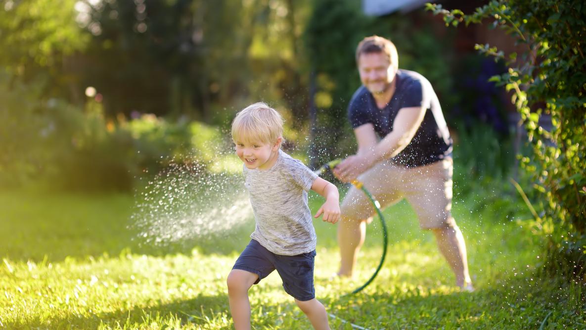 Far spruter vann på sønn med hageslange