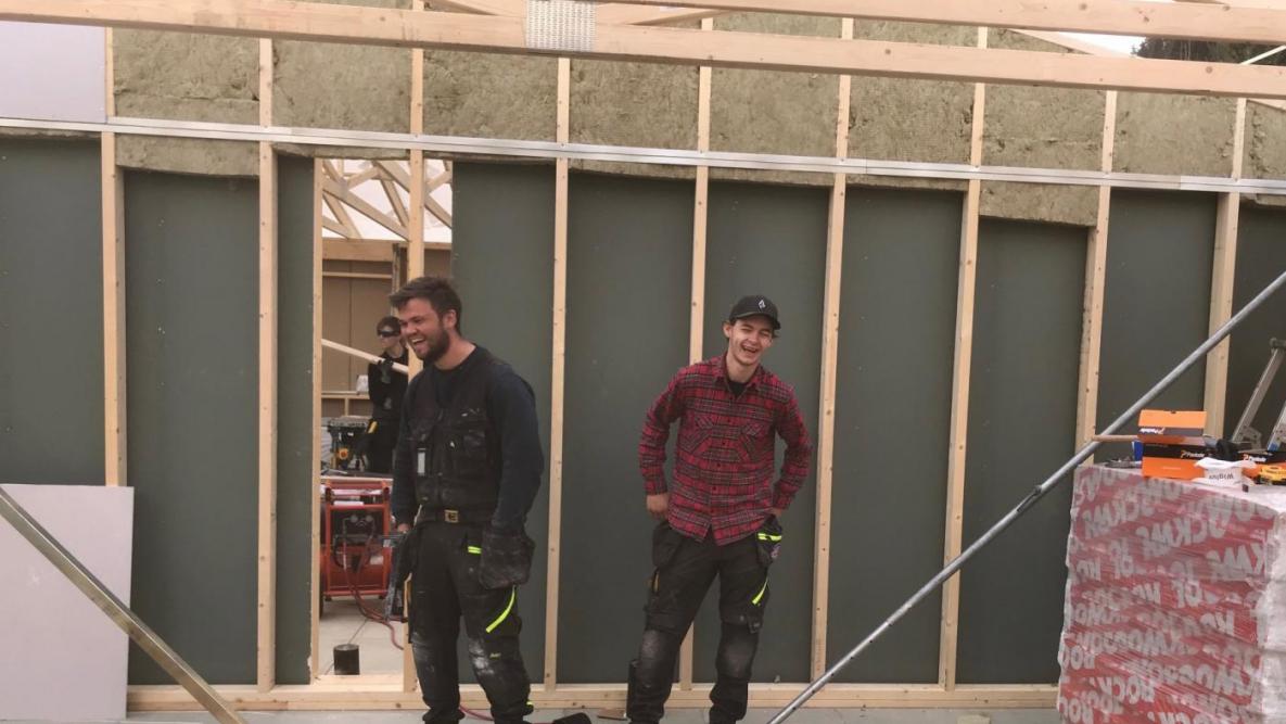 To tømrere ler godt mens de stiller opp for fotografen