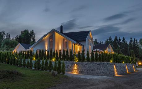 Hvitt hus med flott hage og utebelysning