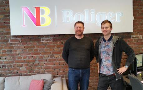 Bjarte Rørvik og Egor Rørvik foran NB Boliger logo på sitt kontor i Ålesund