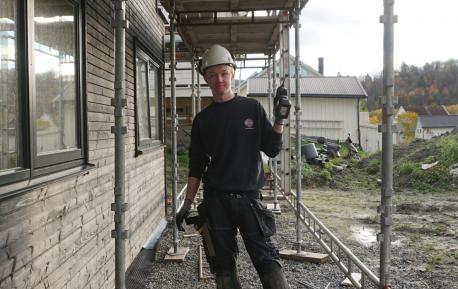 Tømrerlærling Erlend Åsen ute på en byggeplass, holder i en spikerpistol