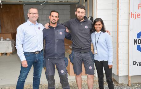 Bildet viser tre smilende Nordbohus-ansatte og en smilende fra Flyktningetjenesten på en byggeplass