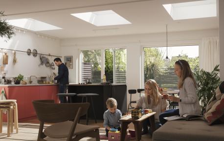 En familie i stue/kjøkken med tre takvinduer som skaper flott lys