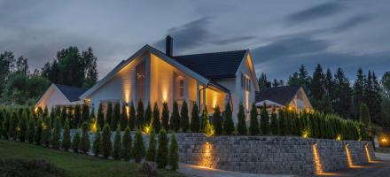 Hvitt hus med flott hage og utebelysning