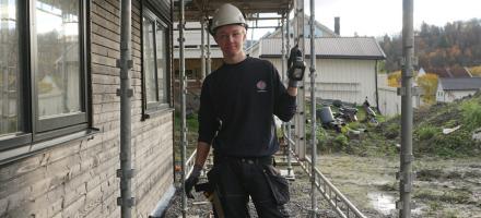 Tømrerlærling Erlend Åsen ute på en byggeplass, holder i en spikerpistol