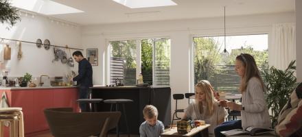 En familie i stue/kjøkken med tre takvinduer som skaper flott lys